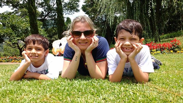 A MOTHER ENJOYING IN THE GARDEN WITH HER CHILDREN AS A HAPPIER FAMILY AFTER ADOPTING CHELSEA ACTON FAMOUS PARENTING STRATEGIES.