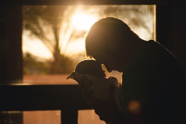 A SINGLE FATHER HOLDING HIS SMALL KID AND LOVING.