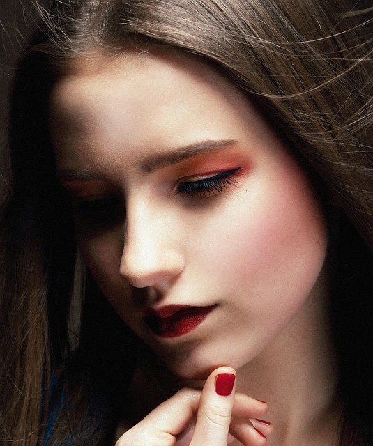 A BEAUTIFUL WOMAN HAS RED NAIL POLISH WITH UNIQUE DESIGN