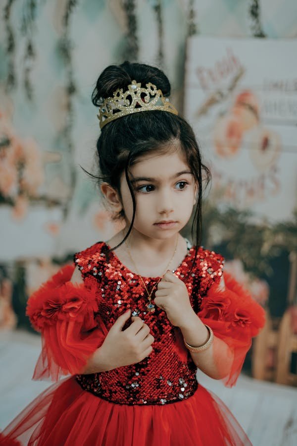 A BABY GIRL WEARING A CROWN A BEAUTIFUL DRESS