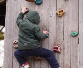 A KID CLIMBING OVER A WALL GETTING TRAINING OF HIKING