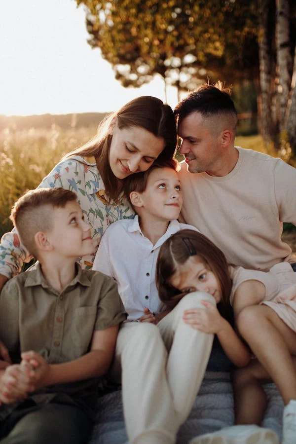 PARENTS ENJOYING PICNIC WITH CHILDREN TO ENCOURAGE OUTDOOR ACTIVITIES