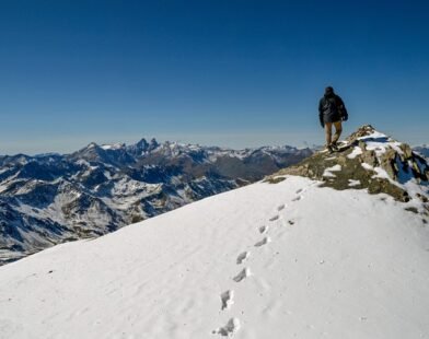 A MAN STANDING ON THE TOP OF MOUNTAIN VICTORIOUSLY