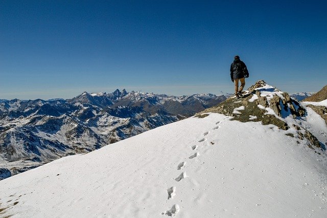 A MAN STANDING ON THE TOP OF MOUNTAIN VICTORIOUSLY