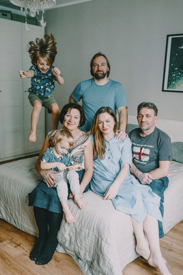 GRAND PARENTS AND CHILDREN SITTING IN THE BEDROOM ENJOYING POSITIVE COMMUNICATION