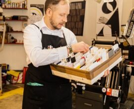A MAN IS WORKING ON HIS PRINTING MACHINE